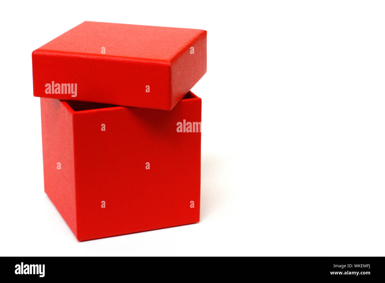 Red gift box with a lid on a white background. There is a place for text. Bright red box without inscriptions. Stock Photo