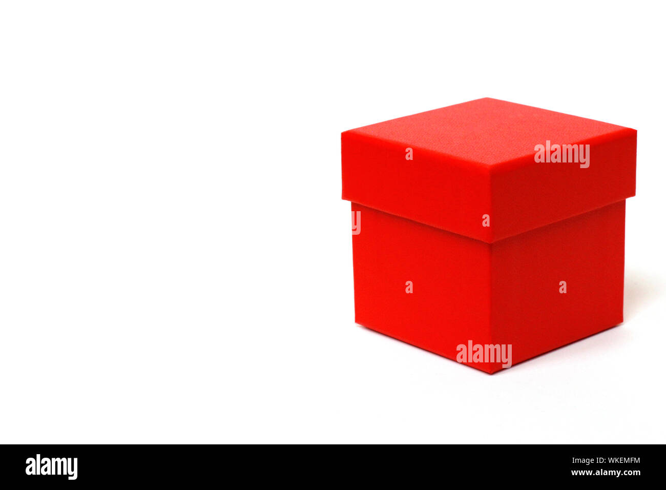 Red gift box with a lid on a white background. There is a place for text. Bright red box without inscriptions. Stock Photo