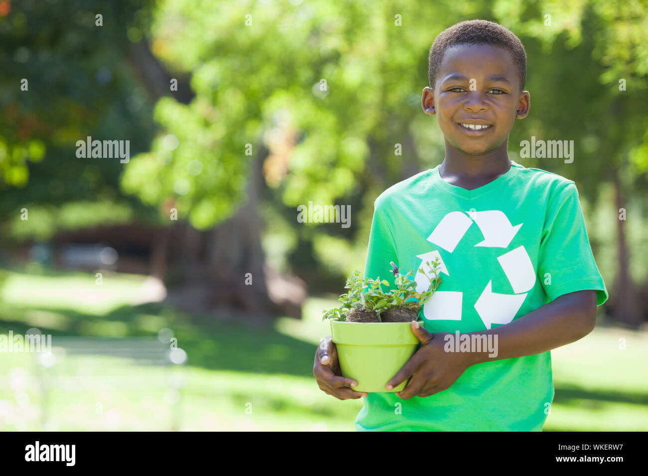 Young boy in recycling tshirt holding potted plant on a sunny day Stock Photo - Alamy