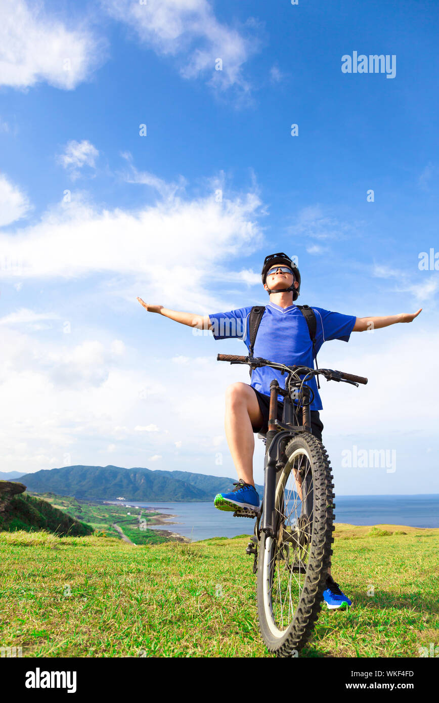young backpacker sitting on a mountain bike and open arms to relax