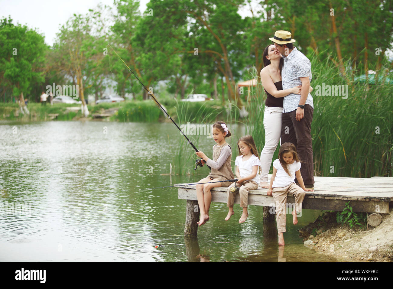 Young happy family with kids fishing in pond in summer Stock Photo