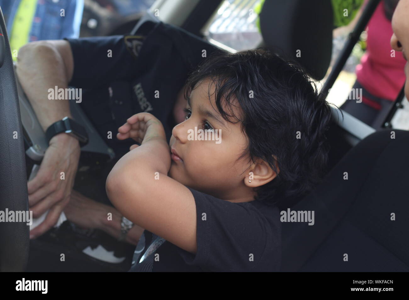 Side View Of Boy Sitting By Female Police Officer In Car Stock Photo
