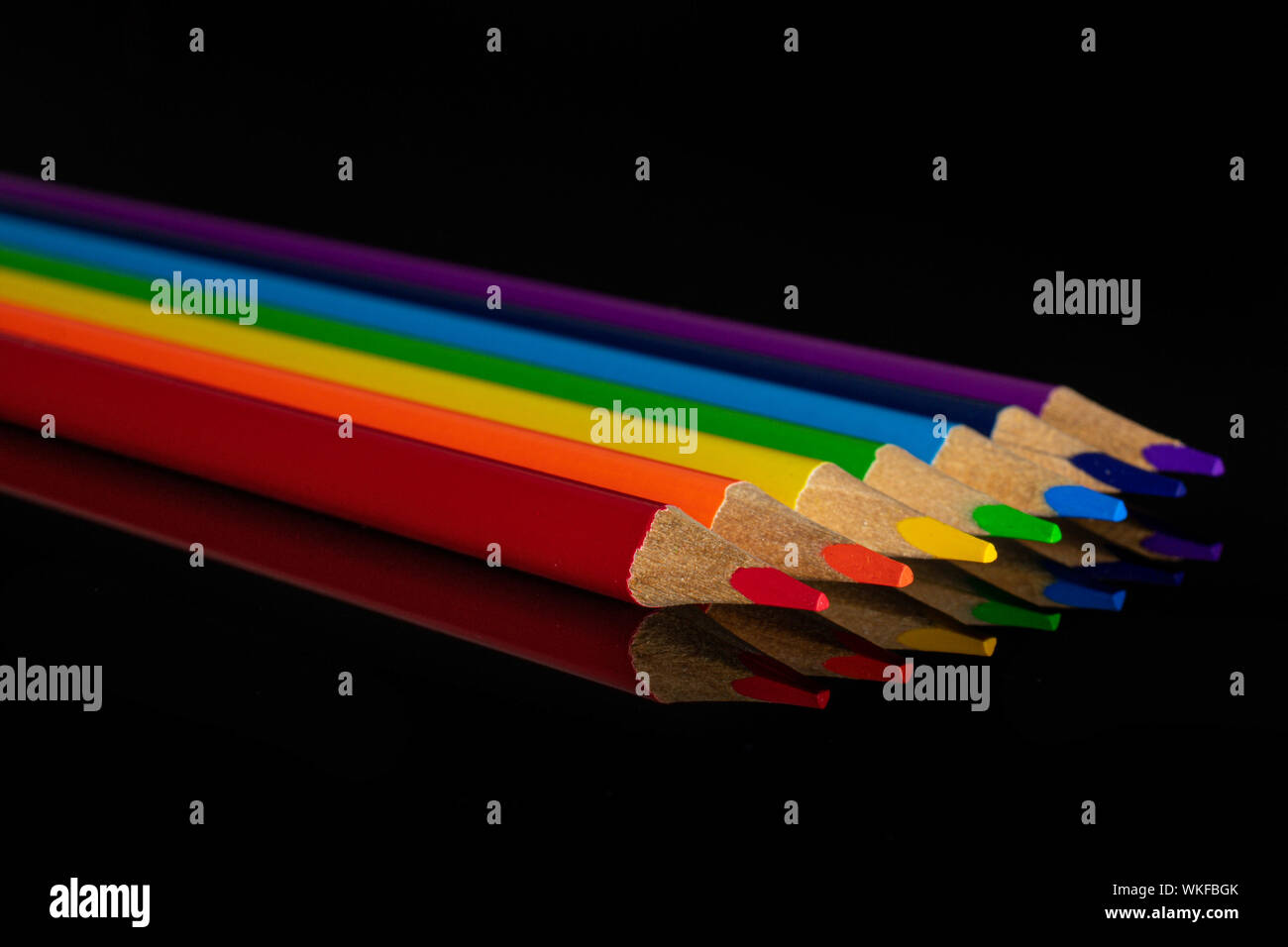 Group of six whole colored pencil rainbow colors isolated on black glass Stock Photo