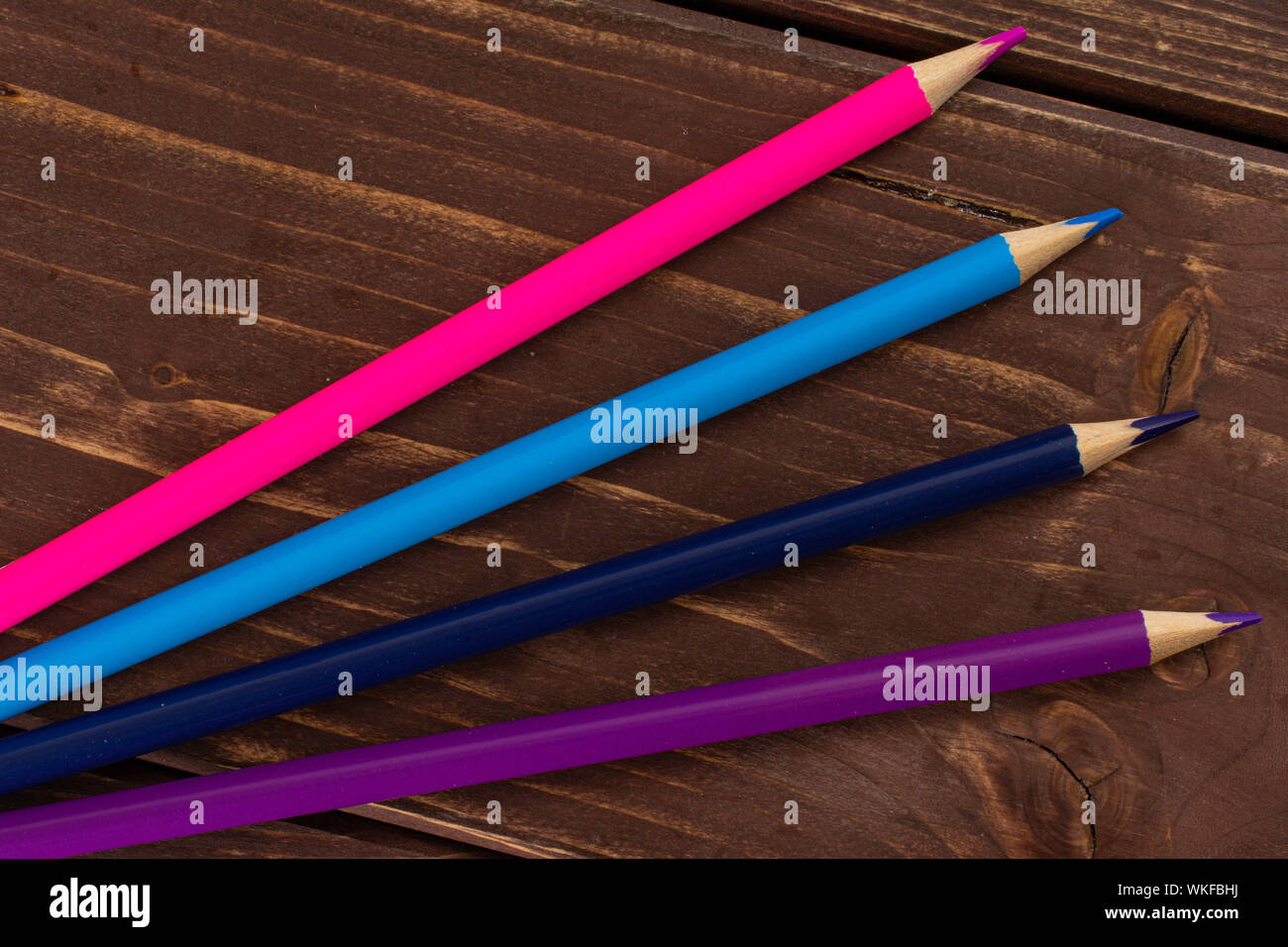 Group of four whole colored pencil flatlay on brown wood Stock Photo