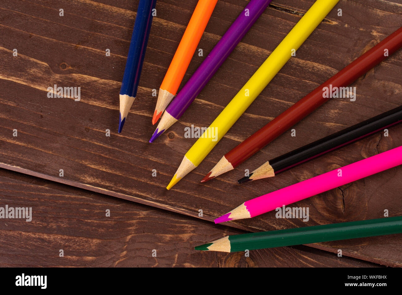 Group of eight whole colored pencil flatlay on brown wood Stock Photo