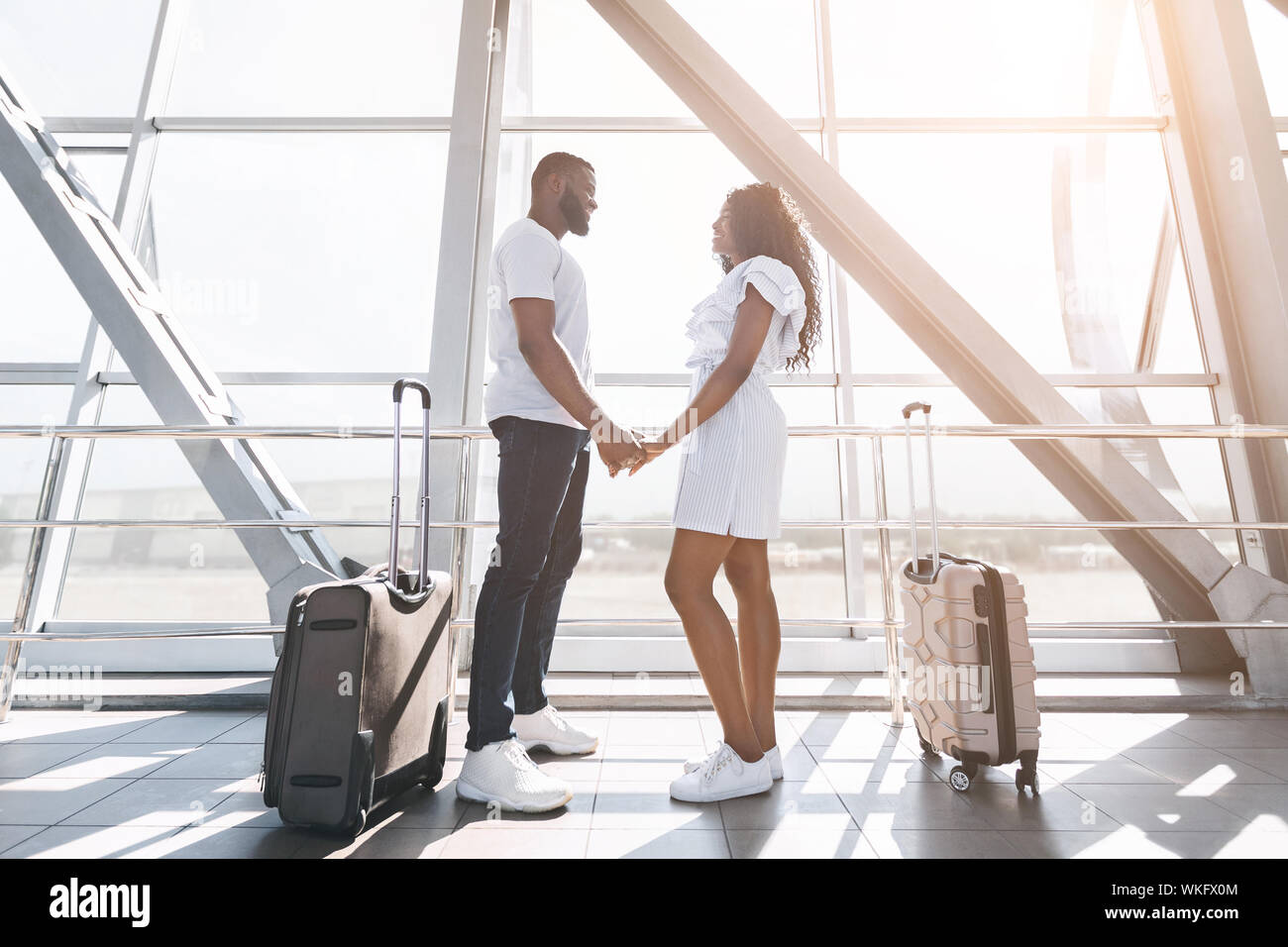 Loving african couple holding hands at airport building Stock Photo - Alamy