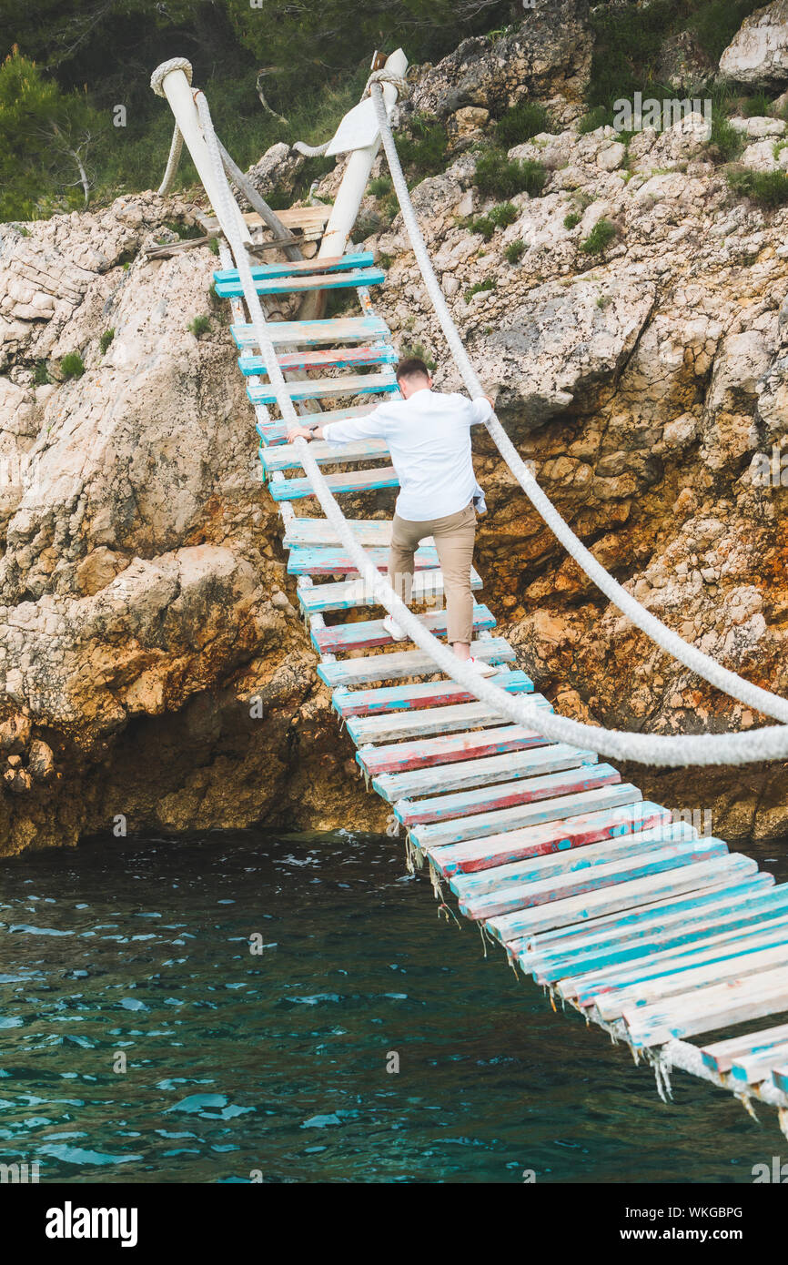 man walking by suspension bridge cross sea Stock Photo - Alamy