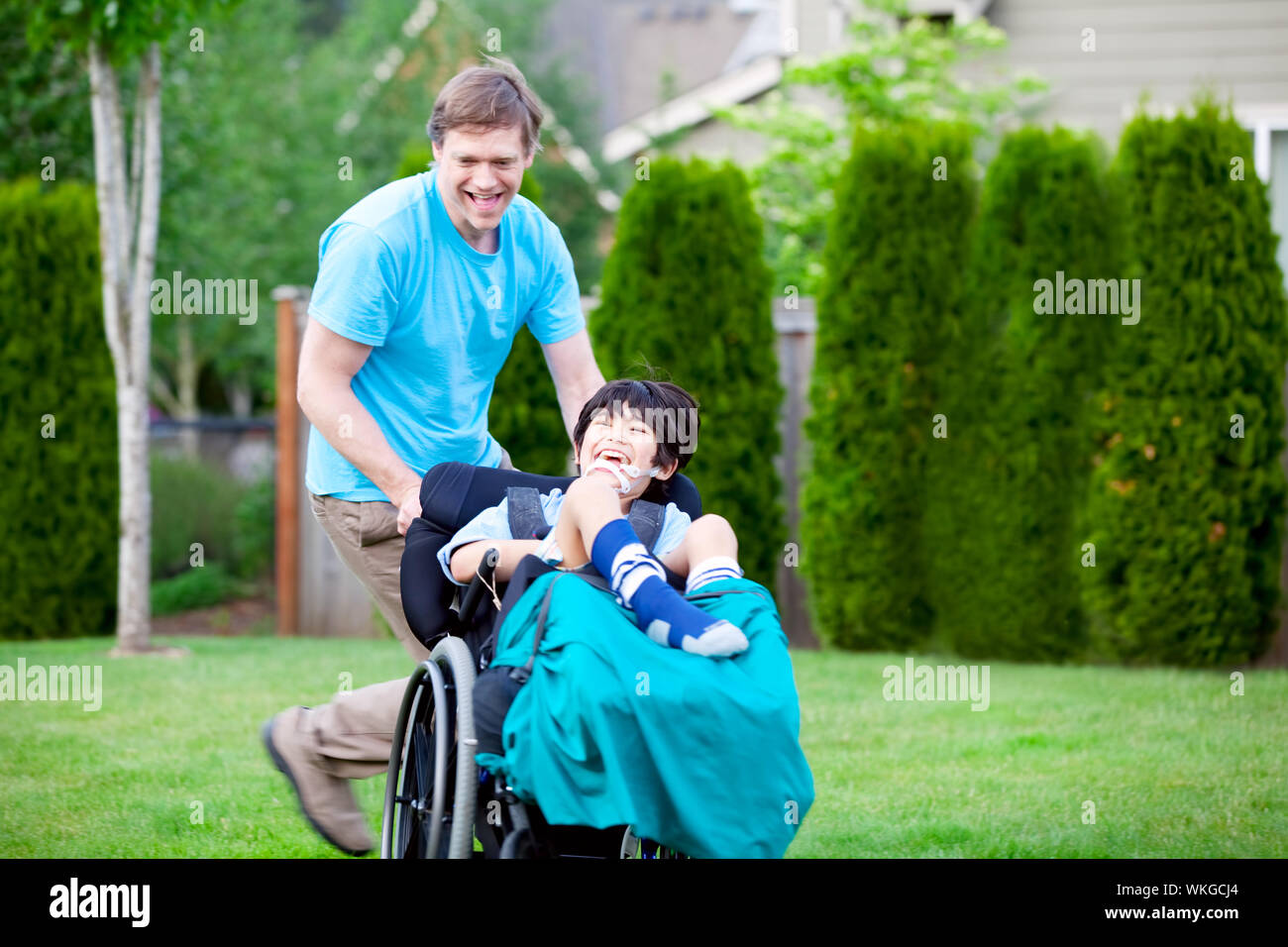 Father racing around park with disabled son in wheelchair Stock Photo ...