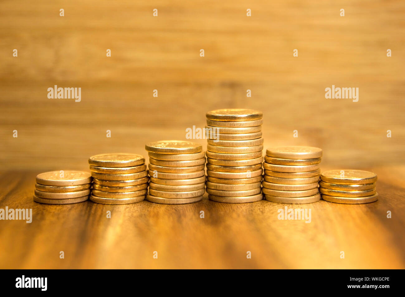 Golden coins piles up and down on wooden background. Selective focus. Stock Photo