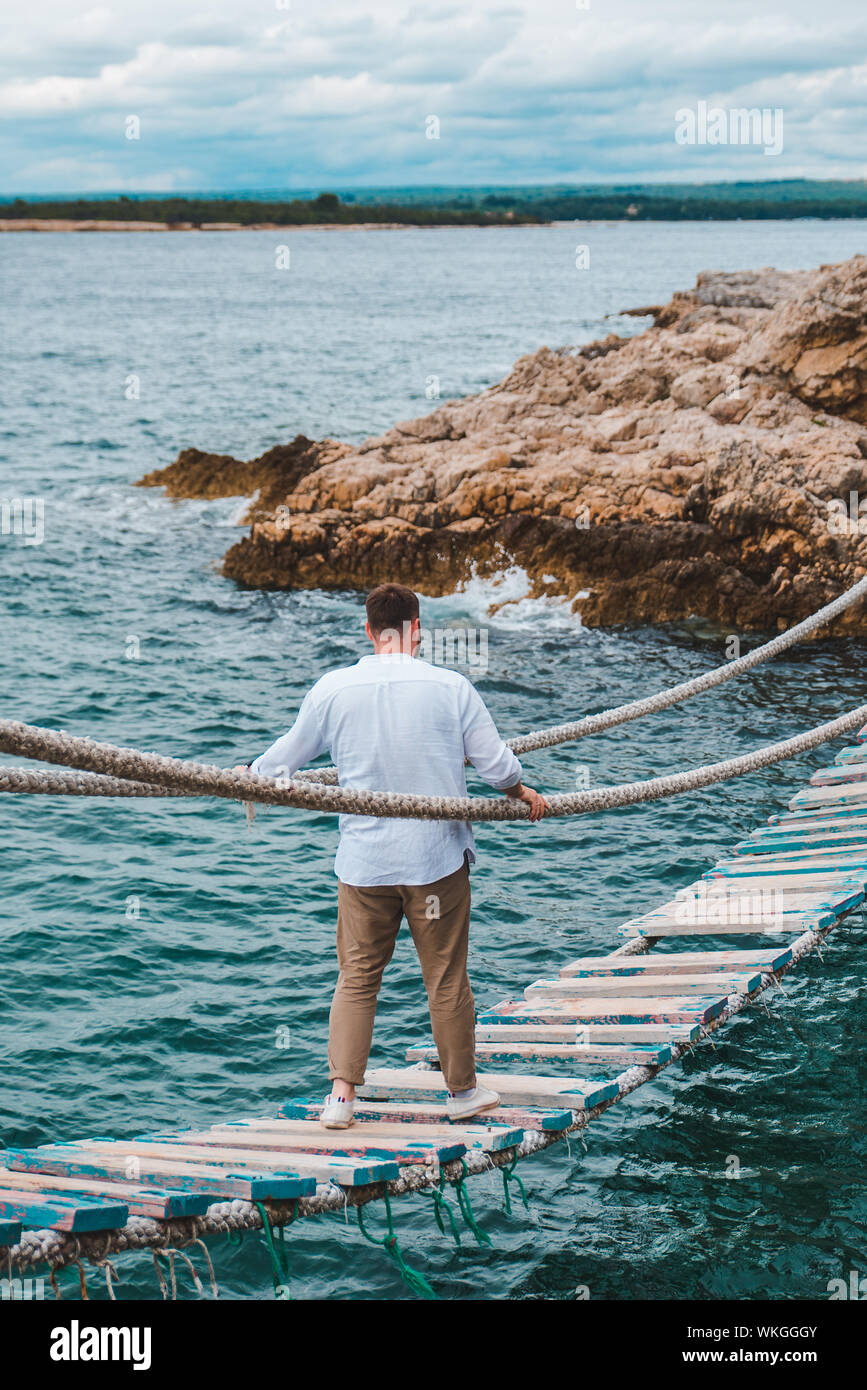 man walking by suspension bridge cross sea bay Stock Photo - Alamy