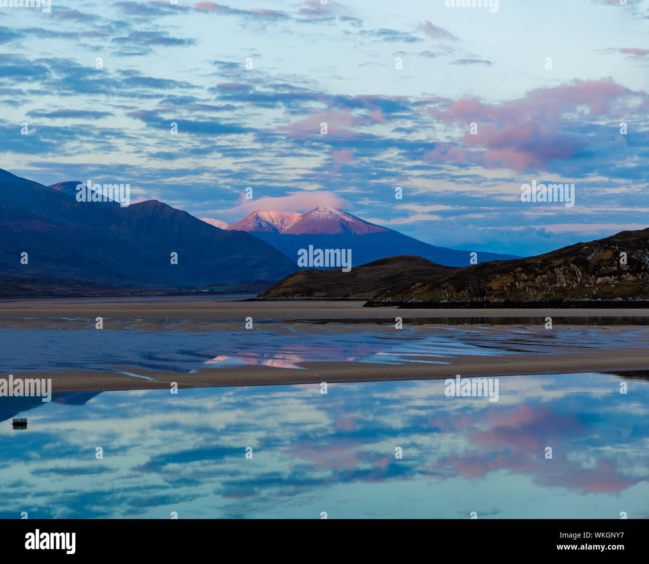 The view from Durness over the Kyle of Durness at sunrise. Beinn Spionnaidh, the snow-capped mountain in the background, lit by the rising sun. In the Stock Photo