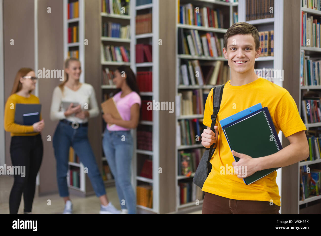 Excited guy posing next to bookshelves in library Stock Photo