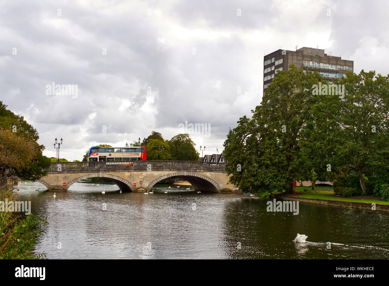 A double-decker bus drives across Bedford town bridge in Bedfordshire, England, UK. The high rise Mecure Bedford Centre Hotel is in the background Stock Photo