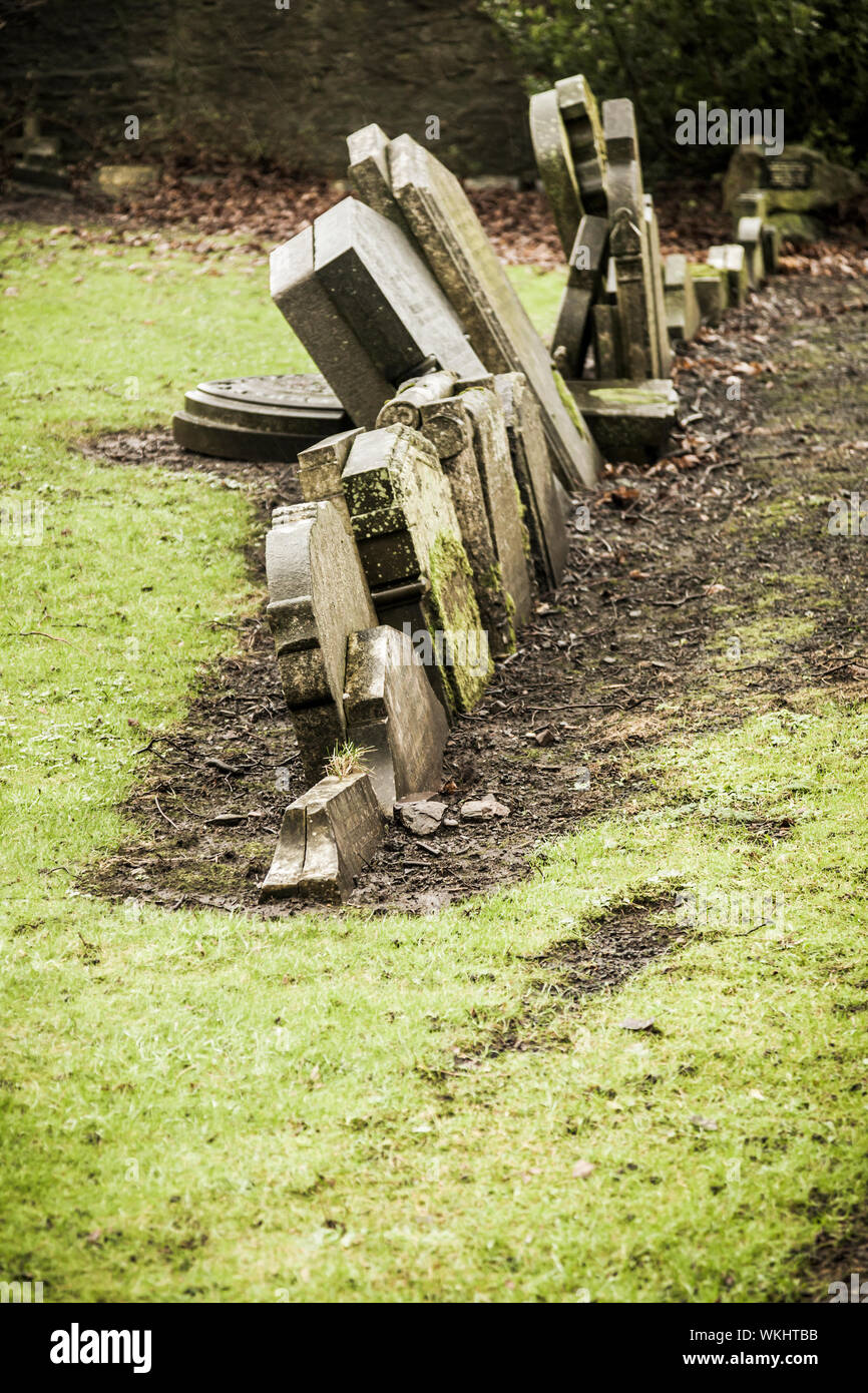 A line of headstones in a graveyard, some of which are falling over. Stock Photo