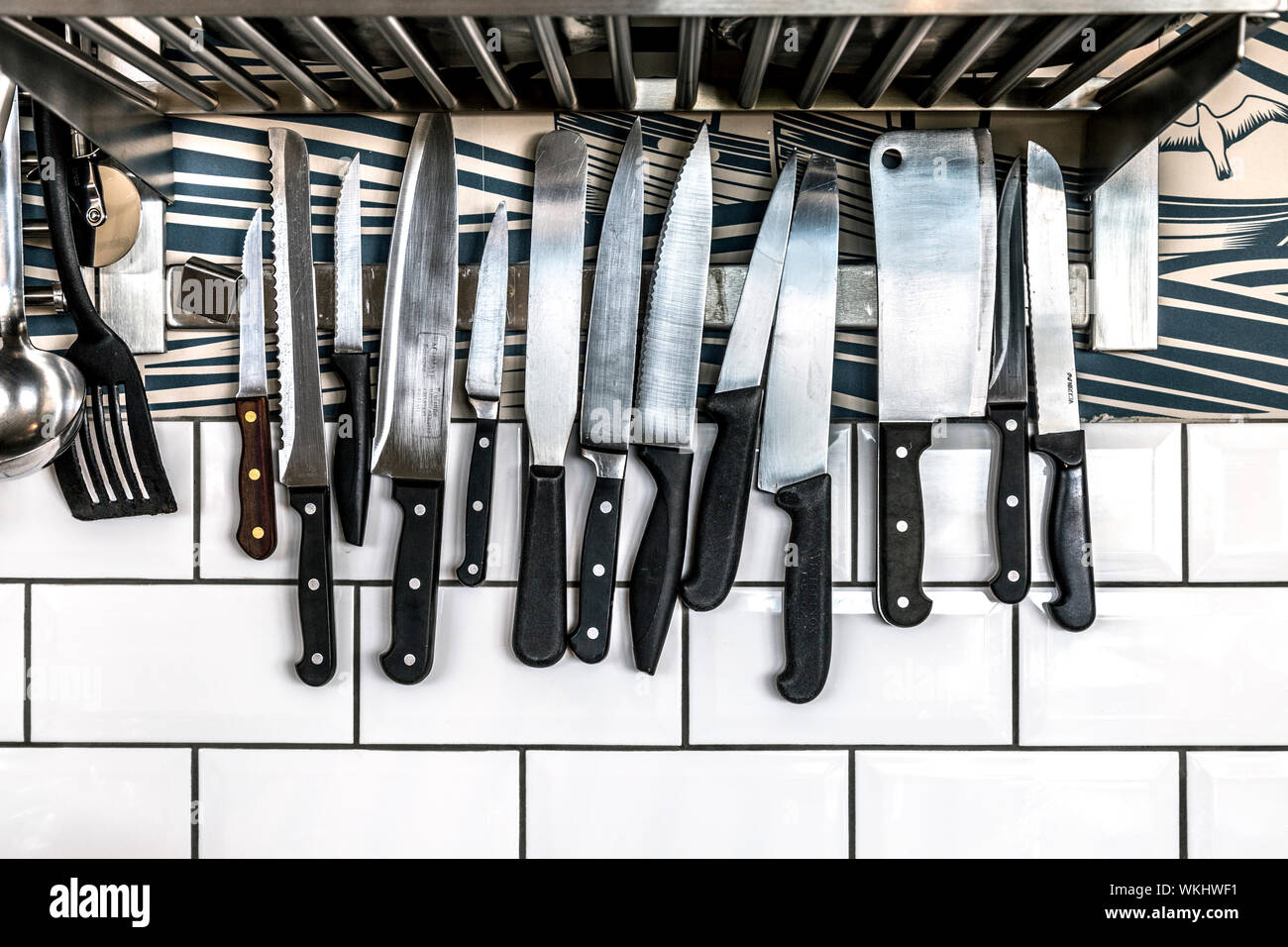 Kitchen knives on a magnetic bar holder on the wall Stock Photo