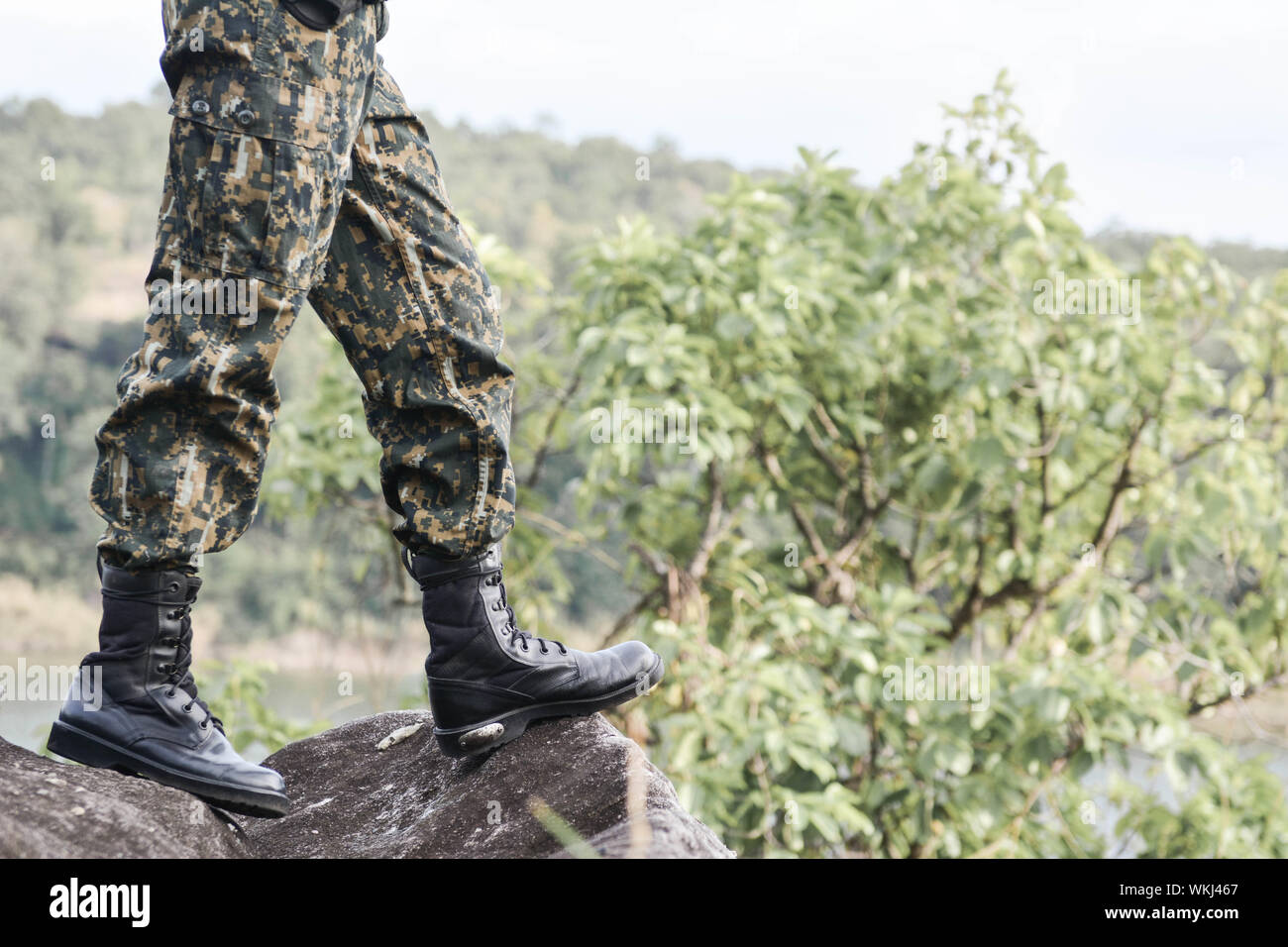 Low Section Of Solider Standing On Rock Against Trees Stock Photo