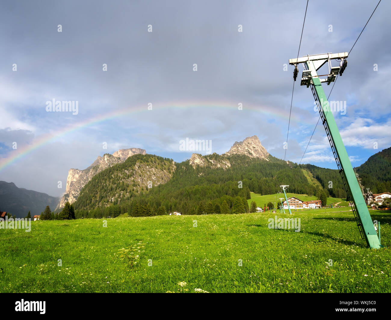 Summer view of Selva di Val Gardena, Italy looking up the ski slope, after rain with genuine rainbow. In Alto Adige, Dolomites. Stock Photo