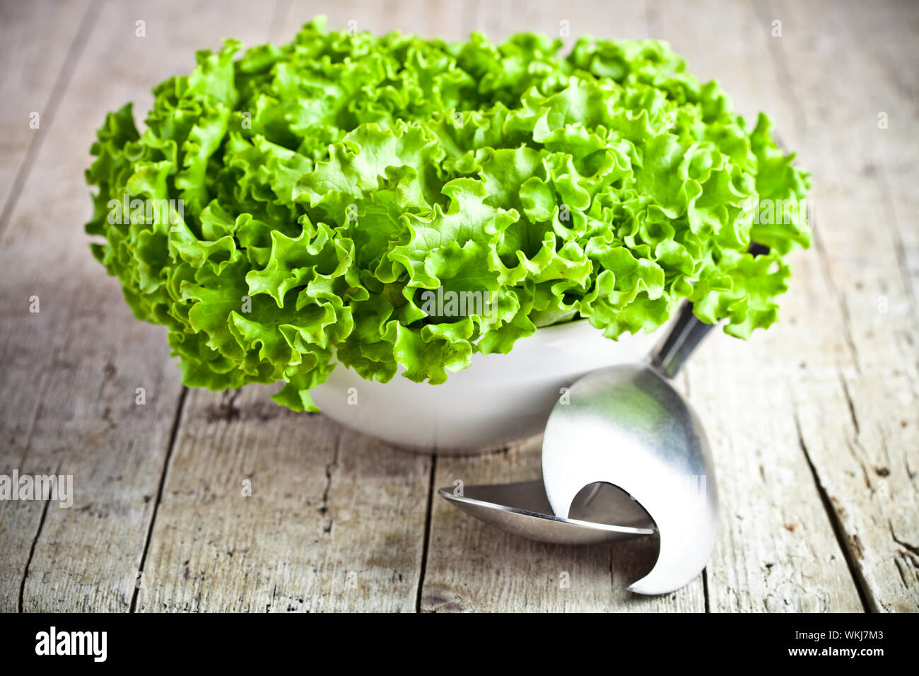 lettuce salad in a bowl and spoons closeup on rustic wooden board Stock Photo - Alamy