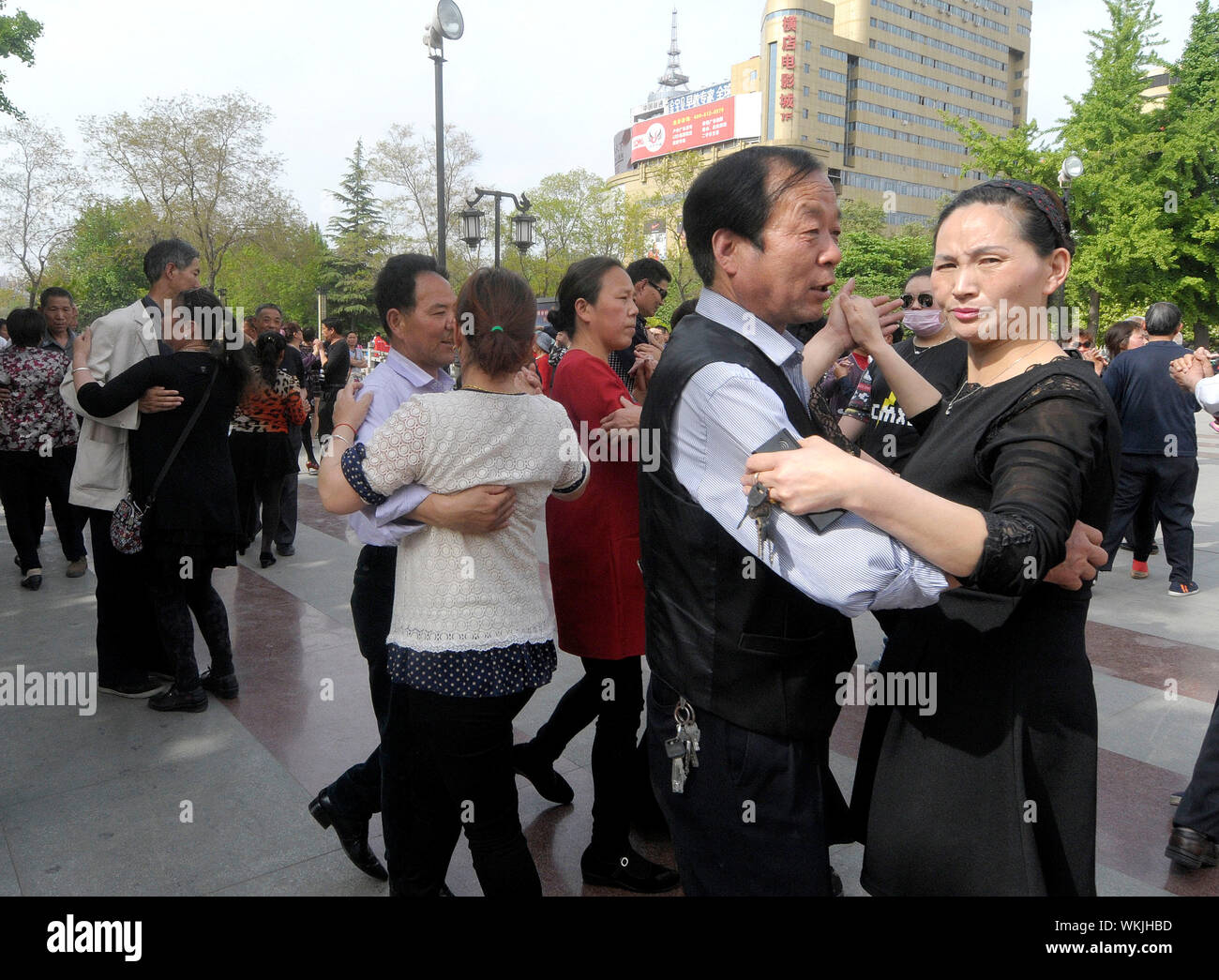 Couples dance to Chinese music on a roadside in Louyang, Henan province of China. Luoyang city was once the capital city of nine dynasties in Chinese Stock Photo