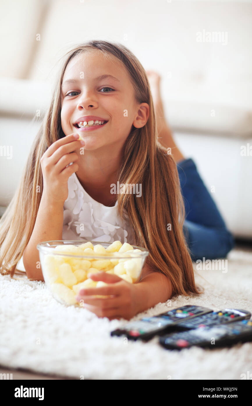 8 years old child watching tv laying down on a white carpet at home