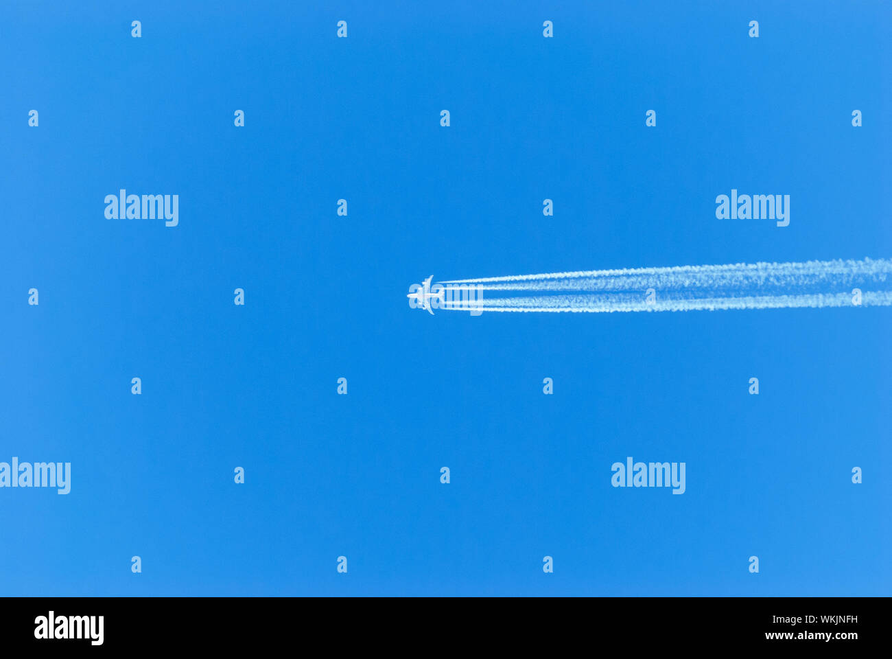 Distant View Of Airplane Flying In Clear Blue Sky Stock Photo