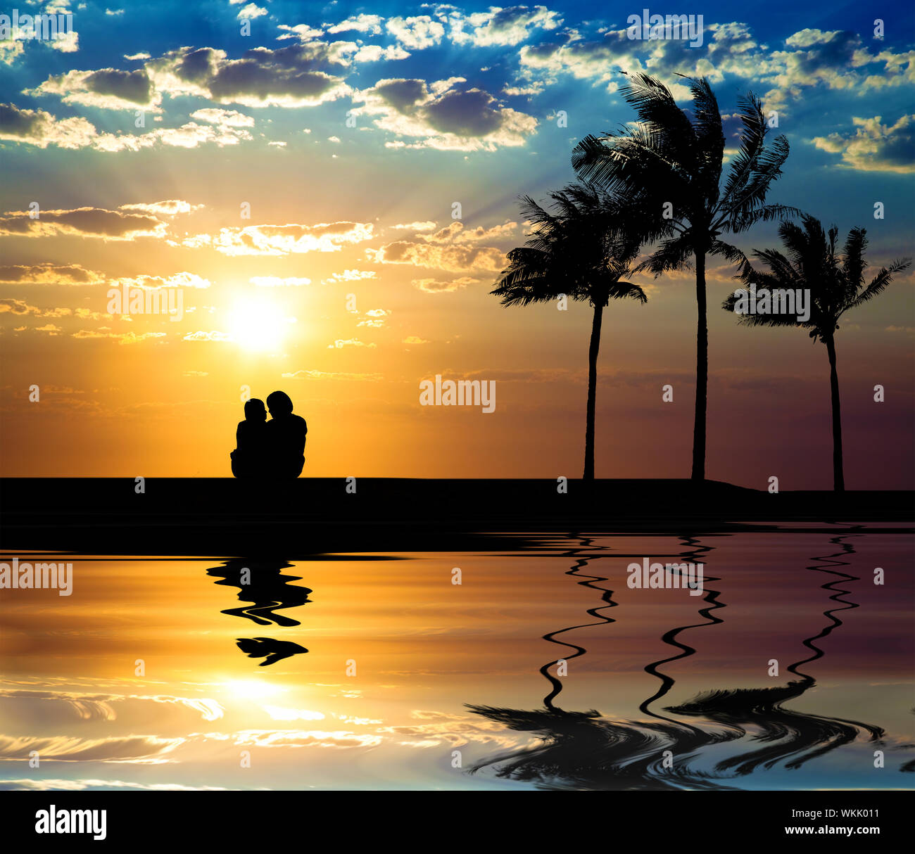 The silhouette of couple watching sunset on the beach Stock Photo - Alamy