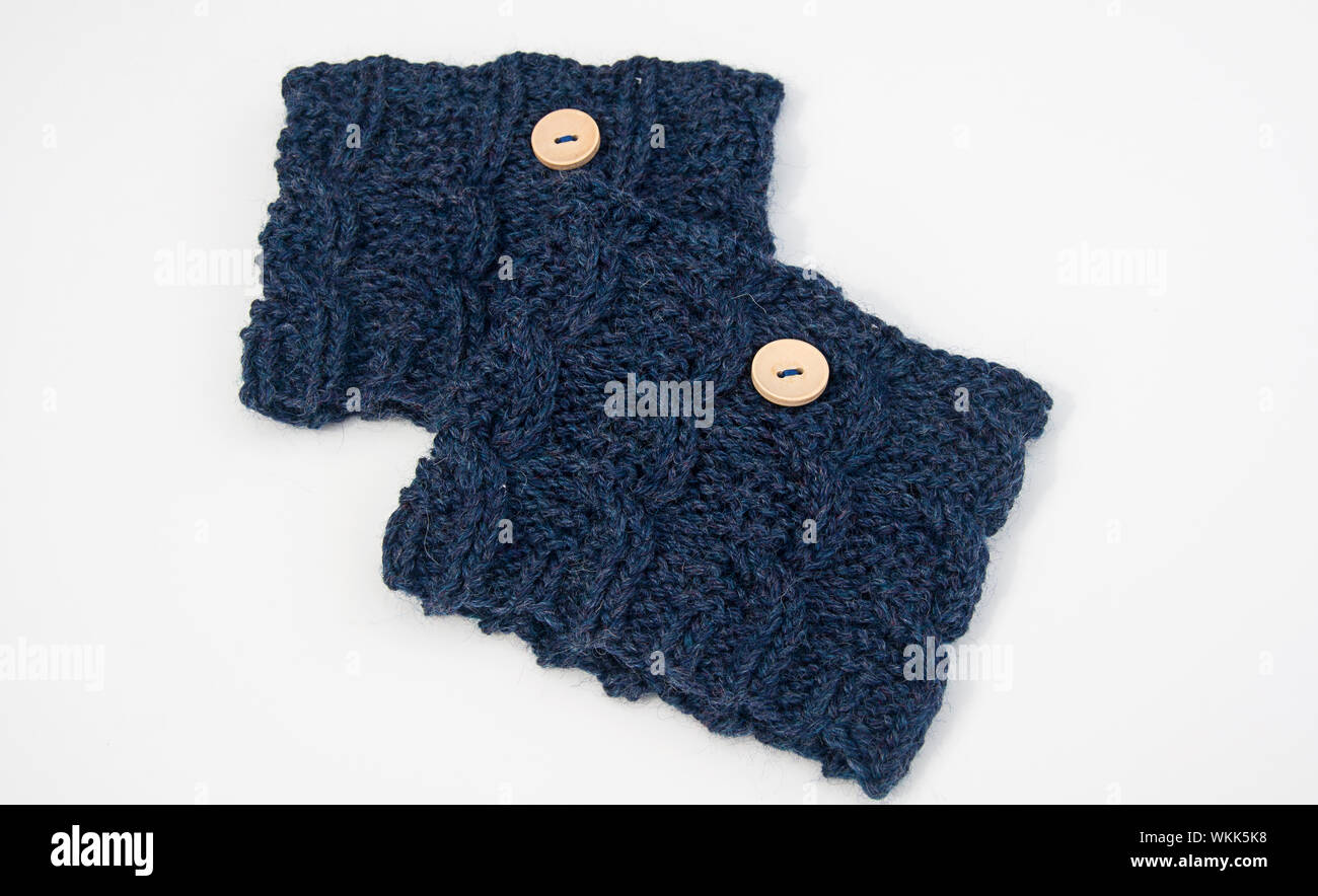 Handknit blue boot cuffs fashion accessory made of wool yarn with slight mauve tones. This fiber art has cable knit stitches with light colored button Stock Photo