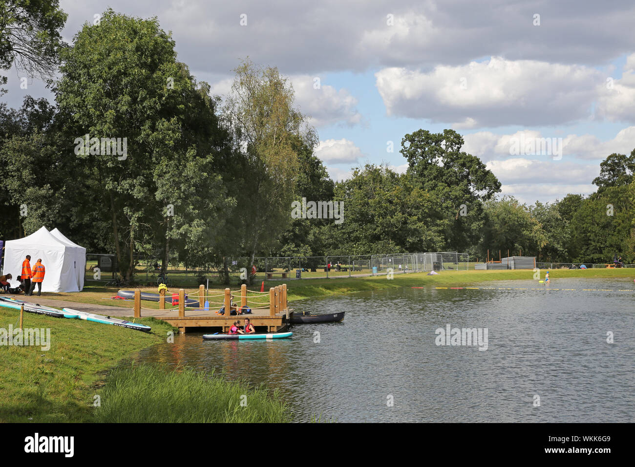 Customers prepare a hired paddle board at the new swimming lake at the recently remodelled Beckenham Place Park, southeast London, UK. Stock Photo