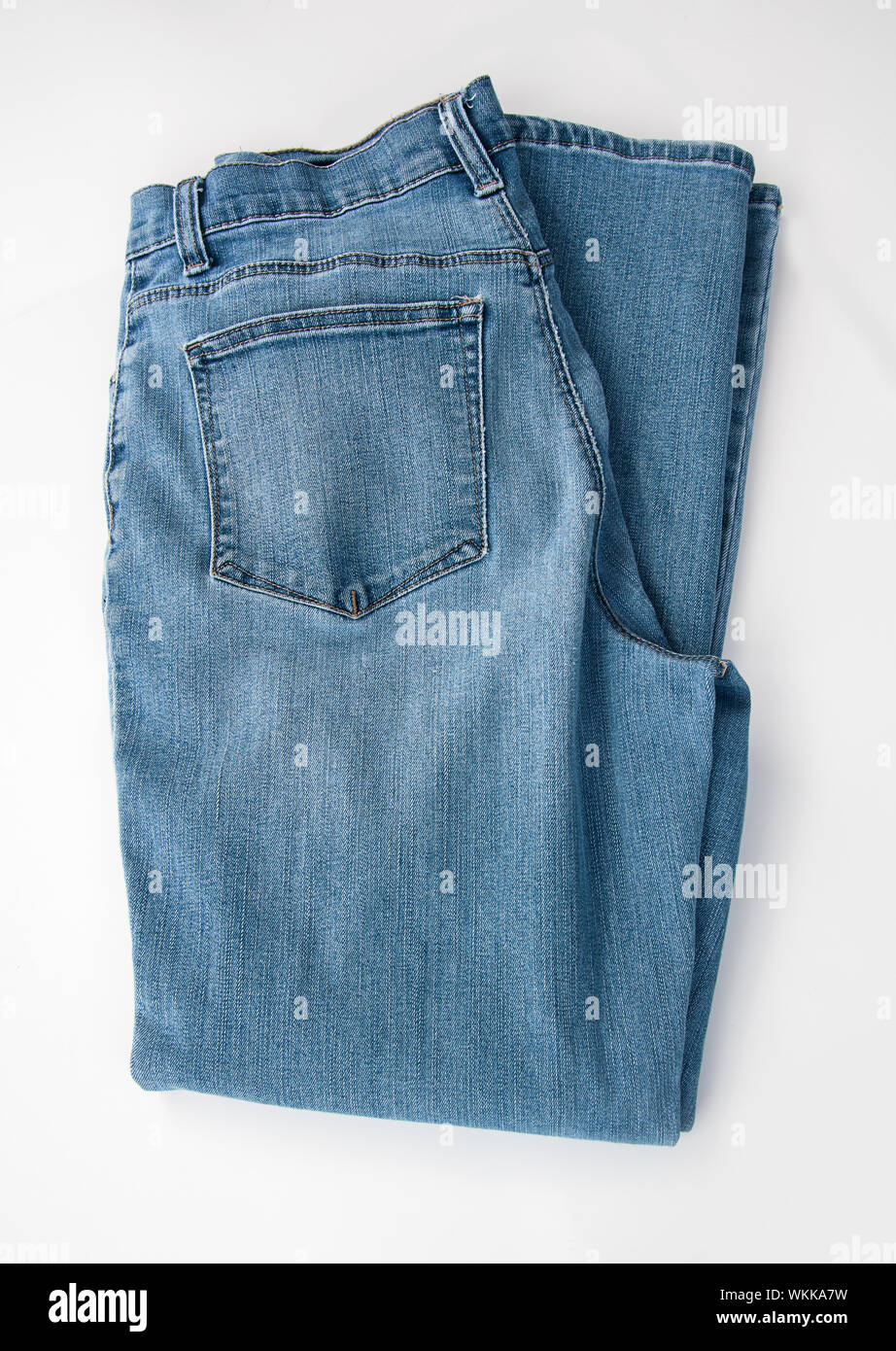 Pair of denim blue jeans folded and isolated on a light background.  A classic staple of casual fashion clothing. Stock Photo
