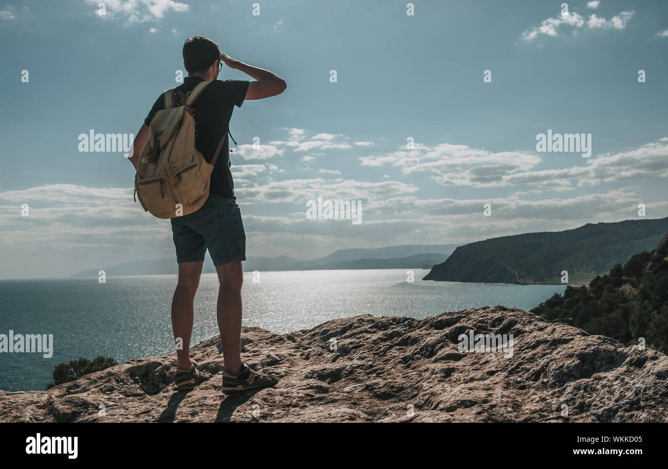 Hiker with backpack standing on top of a mountain with raised hands and ...