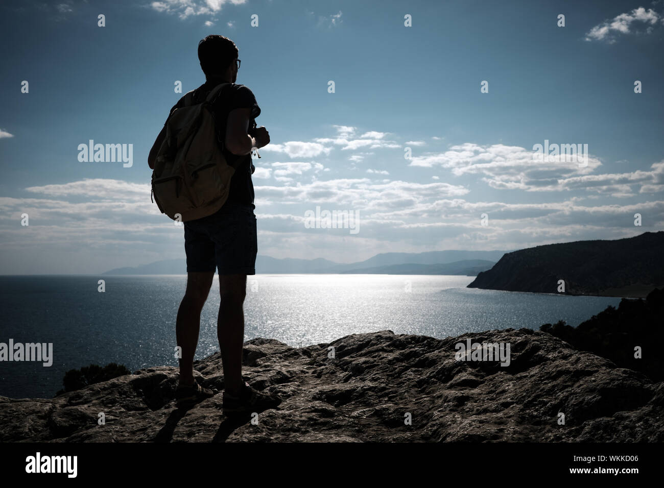 Hiker with backpack standing on top of a mountain with raised hands and ...