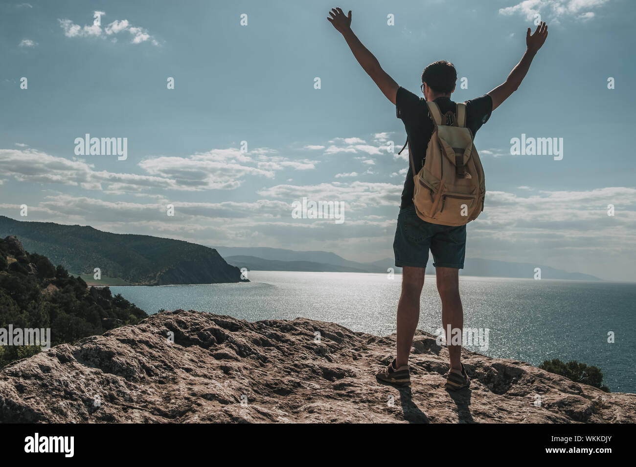 Hiker with backpack standing on top of a mountain with raised hands and ...