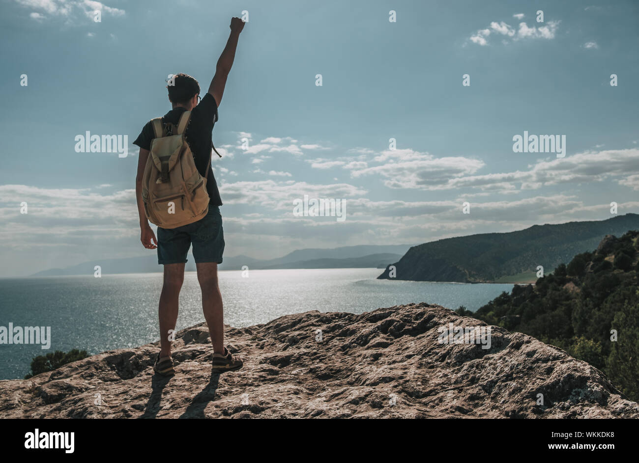 Hiker with backpack standing on top of a mountain with raised hands and ...
