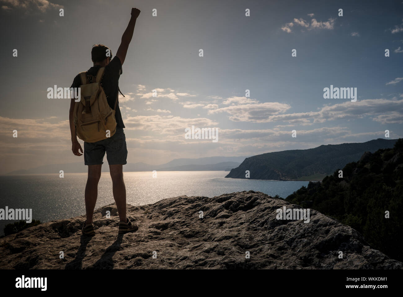 Hiker with backpack standing on top of a mountain with raised hands and ...