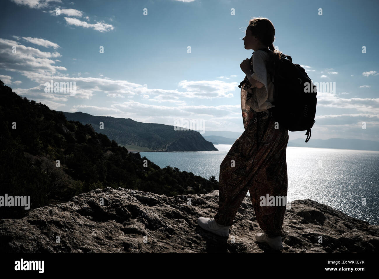 Hiker with backpack standing on top of a mountain with raised hands and ...
