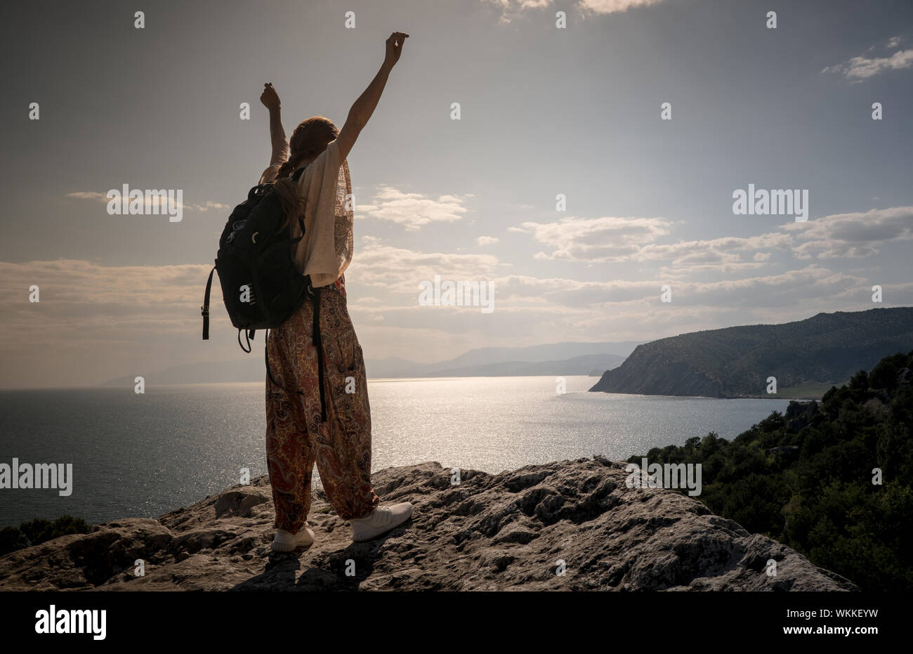 Hiker with backpack standing on top of a mountain with raised hands and ...