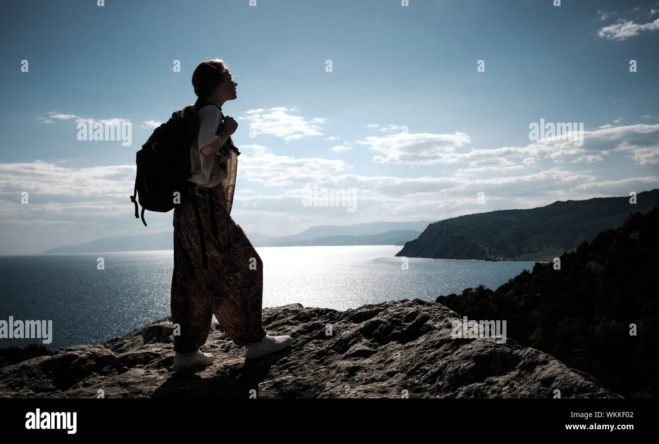 Hiker with backpack standing on top of a mountain with raised hands and ...
