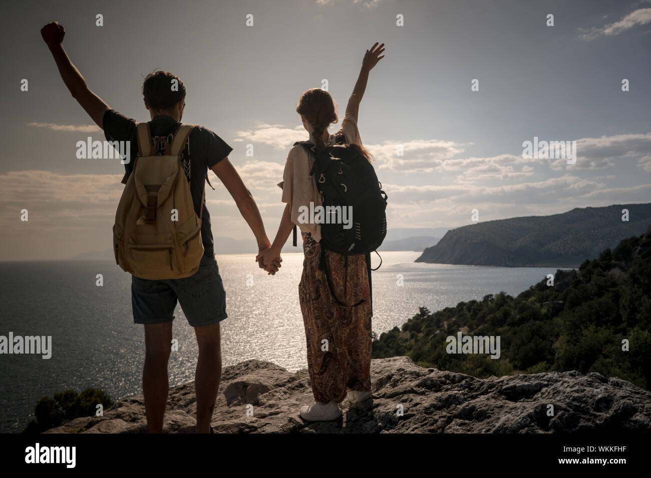 Hikers with backpack standing on top of a mountain with raised hands ...