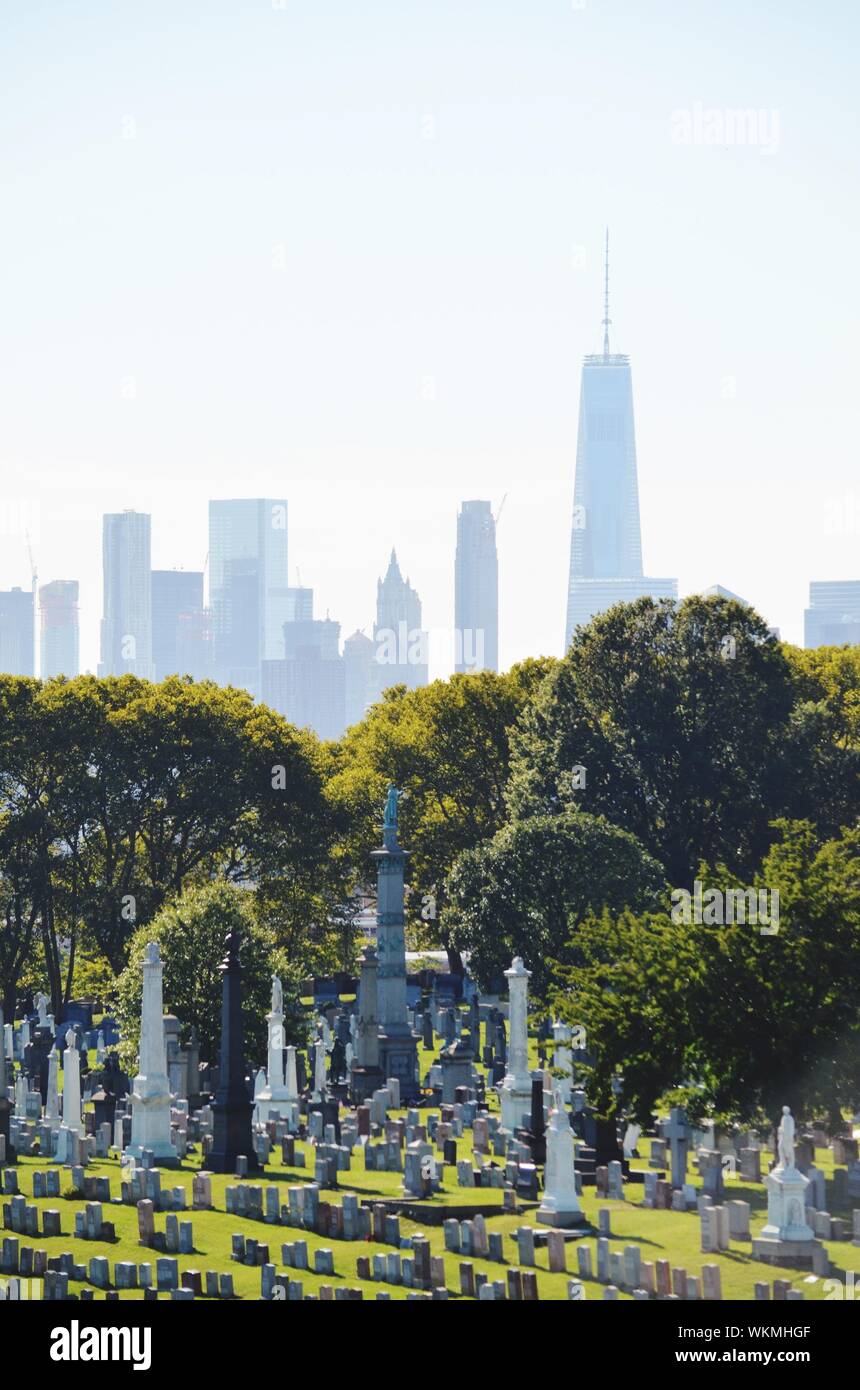 Cemetery By Cityscape Against Sky Stock Photo