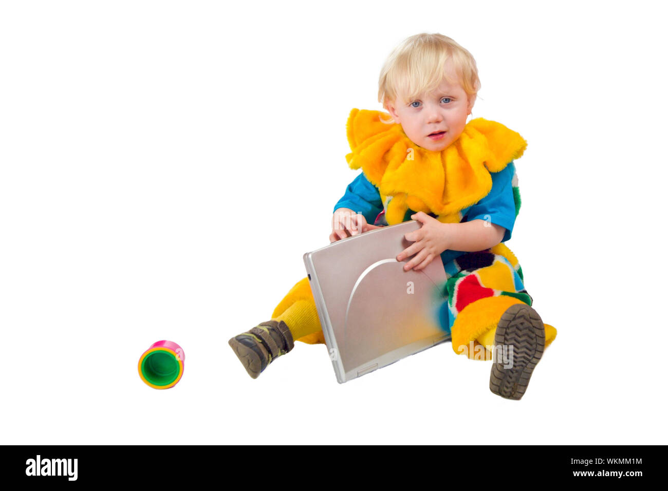 Sad child wearing clown costume holding laptop isolated on white Stock Photo