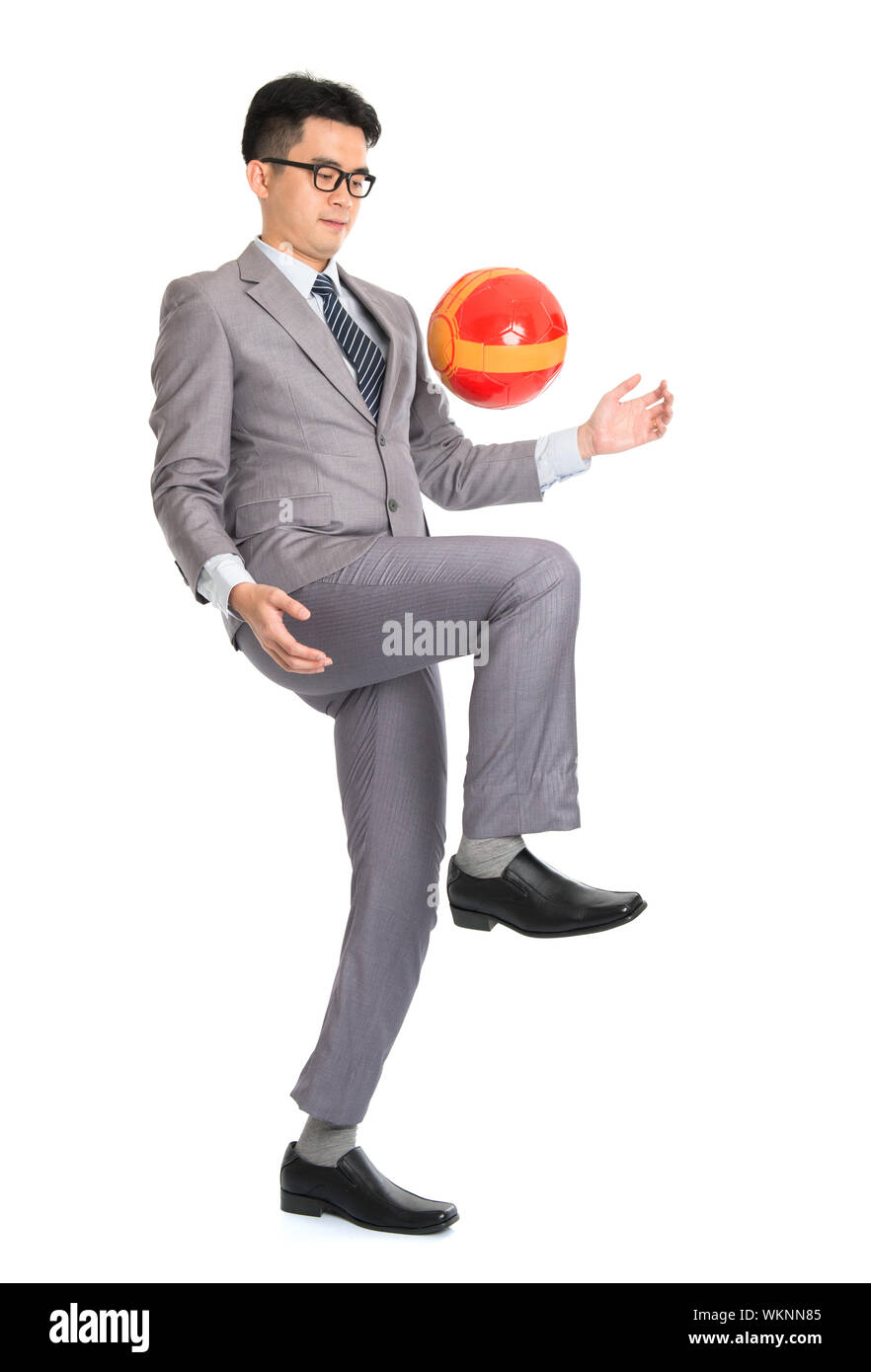 Portrait of full length Asian businessman playing with soccer ball, isolated on white background. Stock Photo