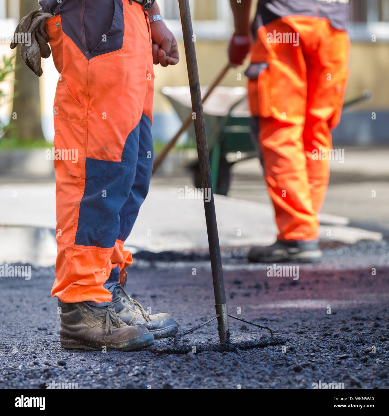 Construction workers during asphalting road works wearing coveralls. Manual labor on