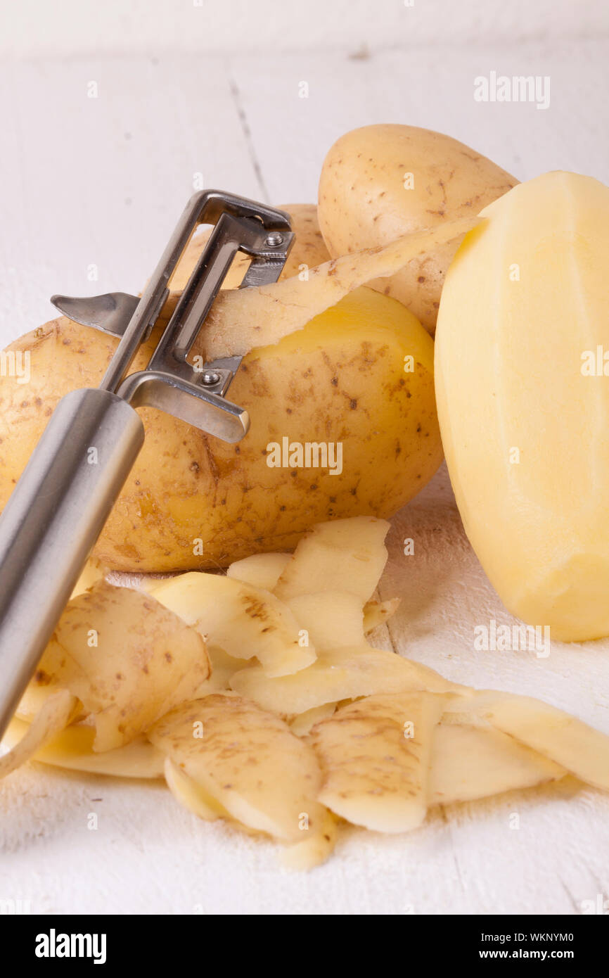 Potatoes with Peeler and Peeled Skin Stock Photo
