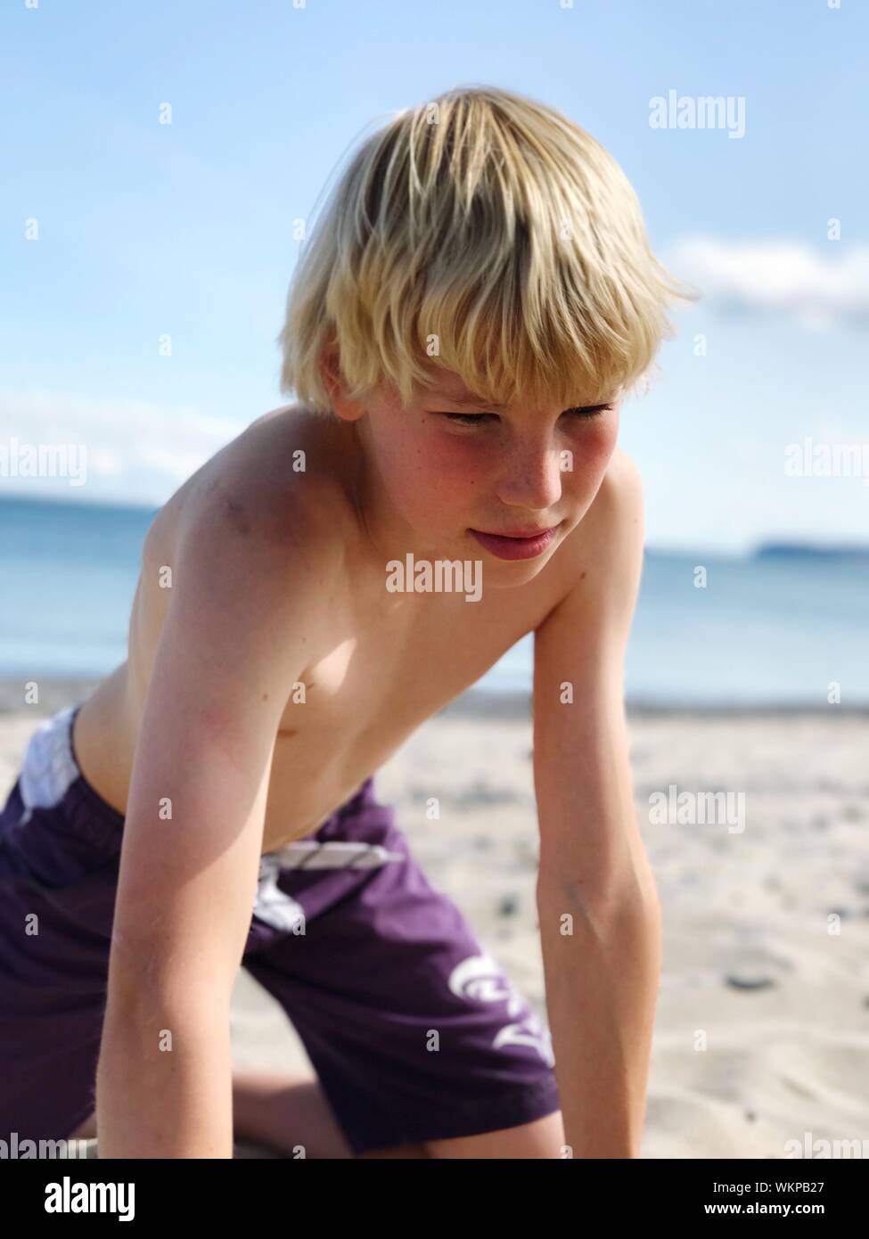 Shirtless Teenage Boy Kneeling At Beach Stock Photo Alamy