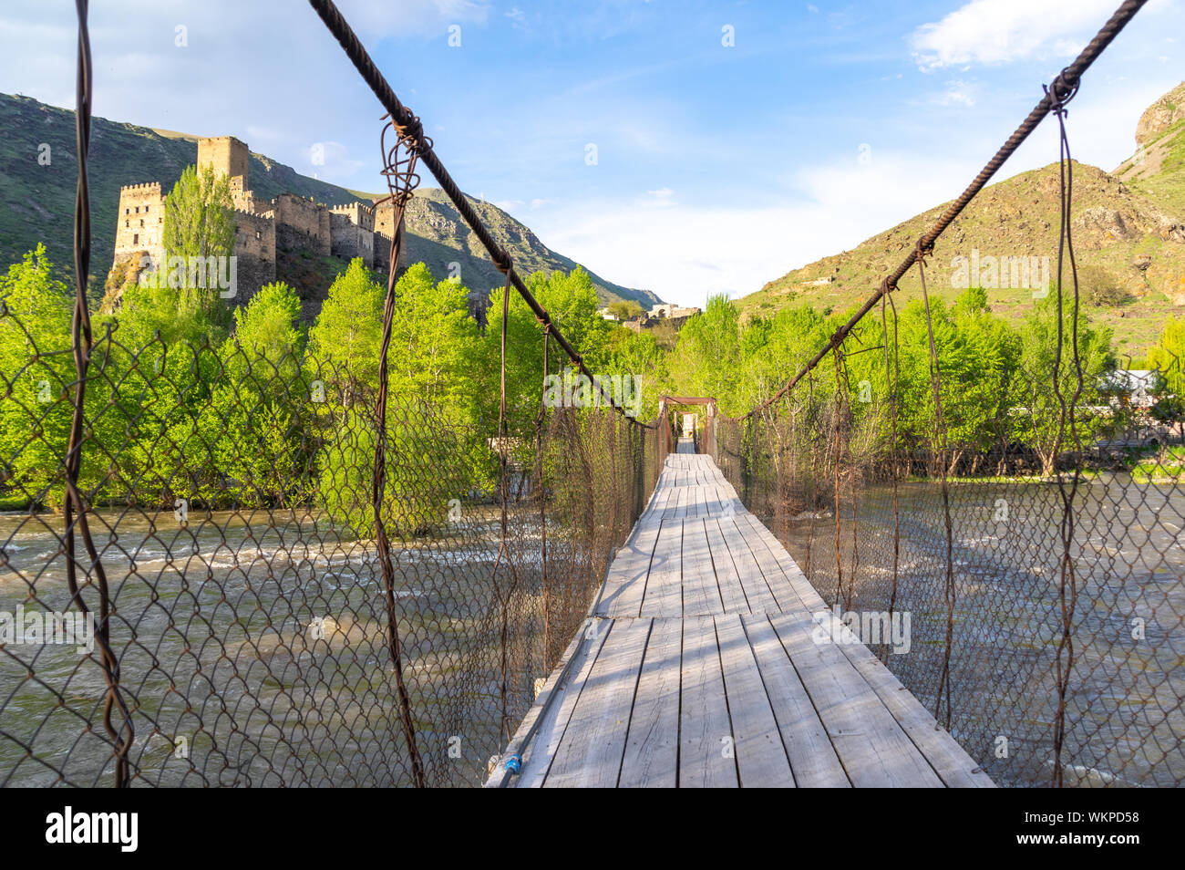 Suspension bridge over the Kura River in the Samtskhe-Javakheti province of Georgia with the Khertvisi fortress in the background Stock Photo