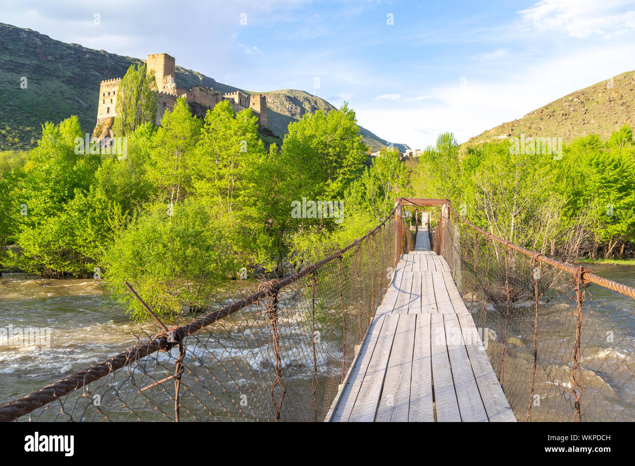 Suspension bridge over the Kura River in the Samtskhe-Javakheti province of Georgia with the Khertvisi fortress in the background Stock Photo