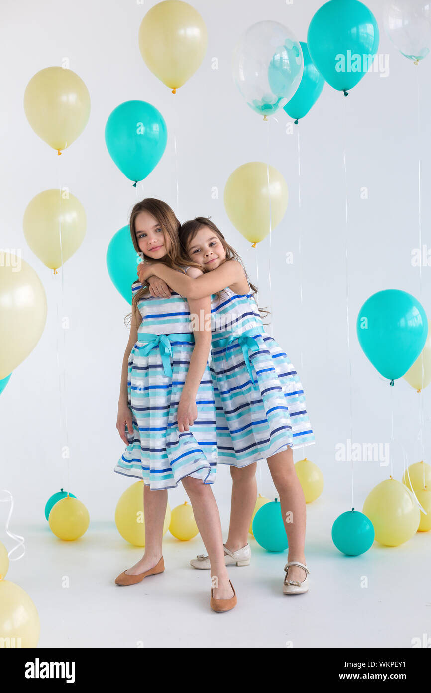 Two girls hugging in a colorful balloons - isolated over a white background Stock Photo