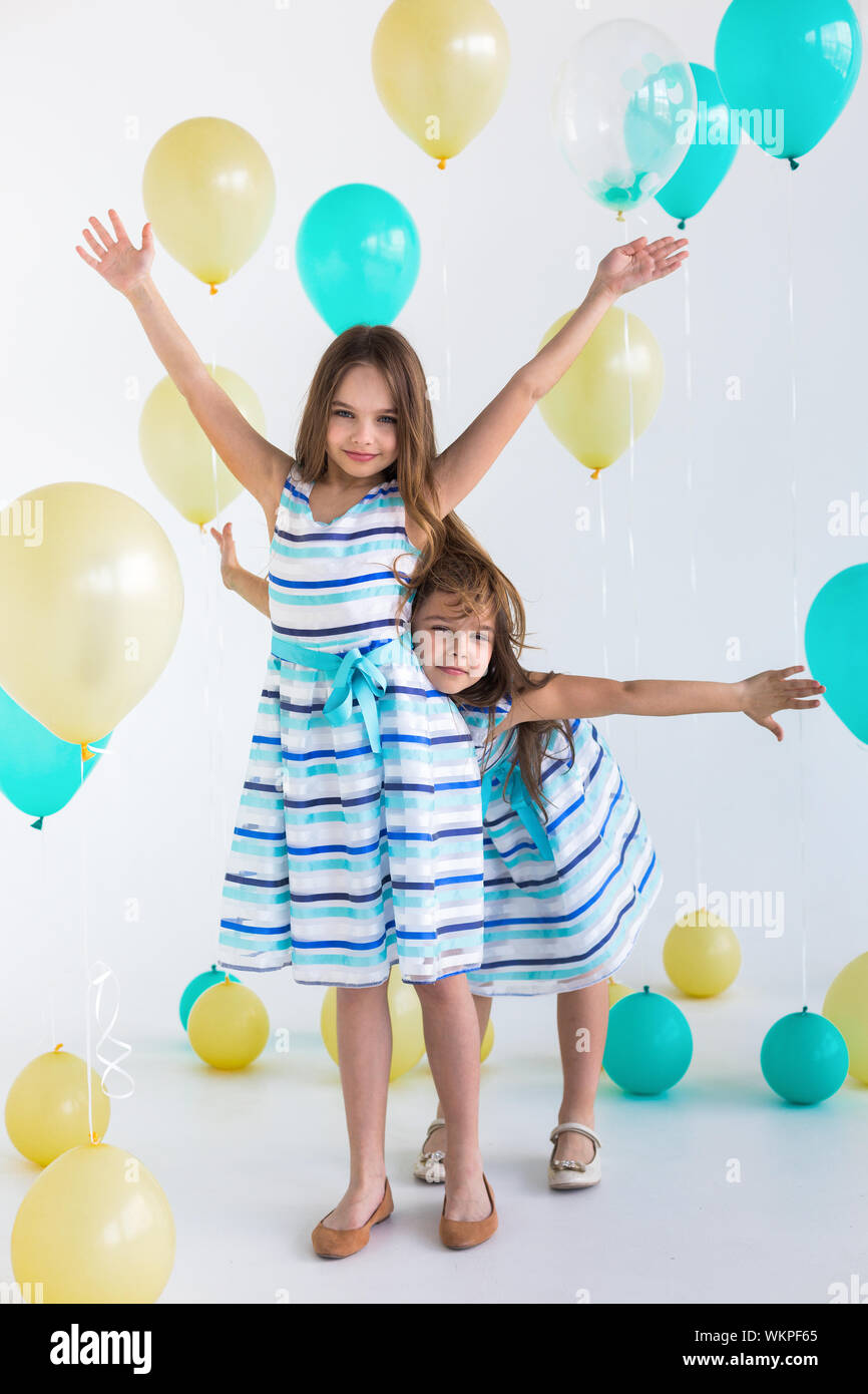 Two girls with colorful balloons and outstretched arms - isolated over a white background Stock Photo