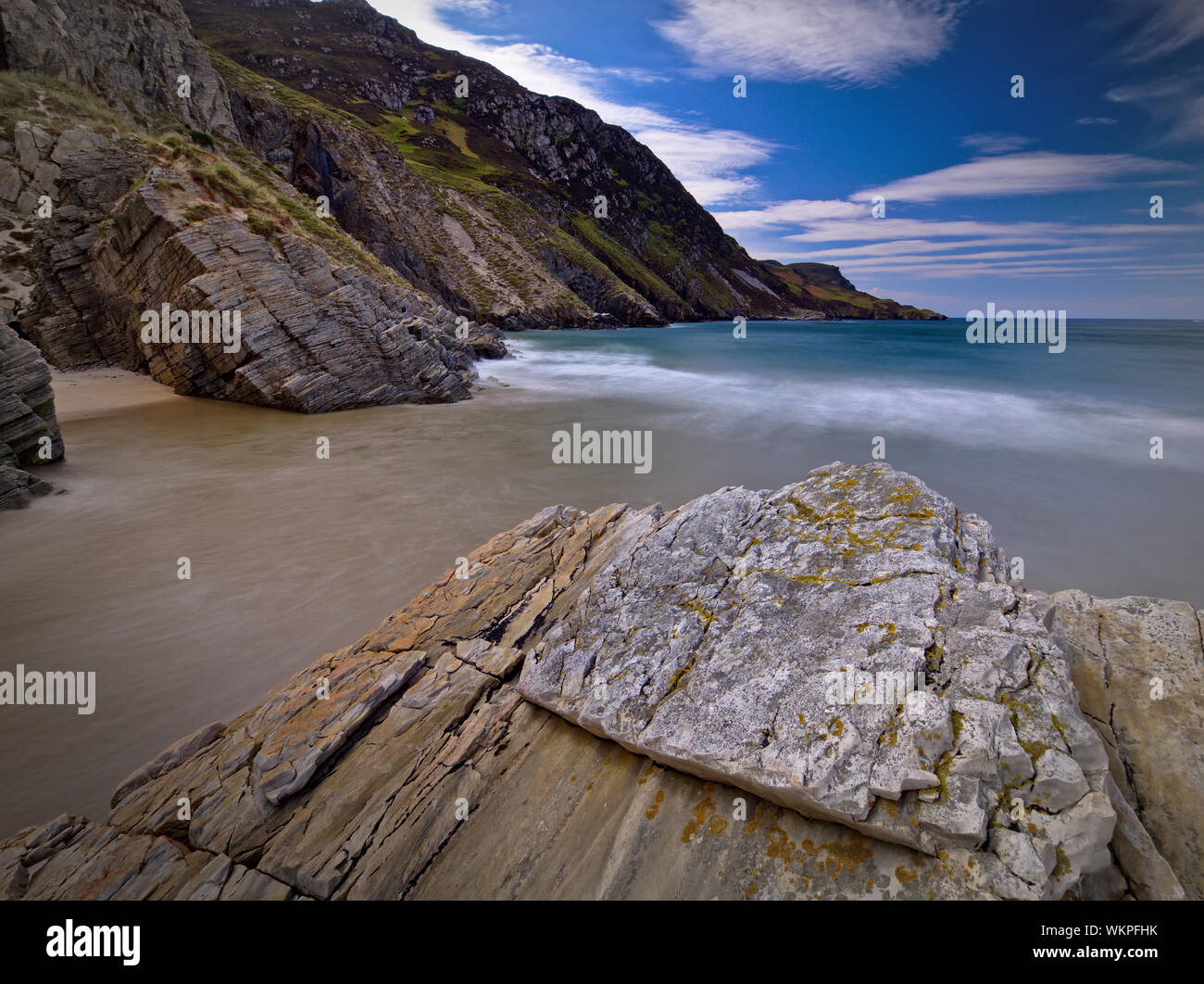Long exposure photo of the incoming tide between the rocks at Maghera Beach, Co. Donegal with huge sea cliffs in the background Stock Photo