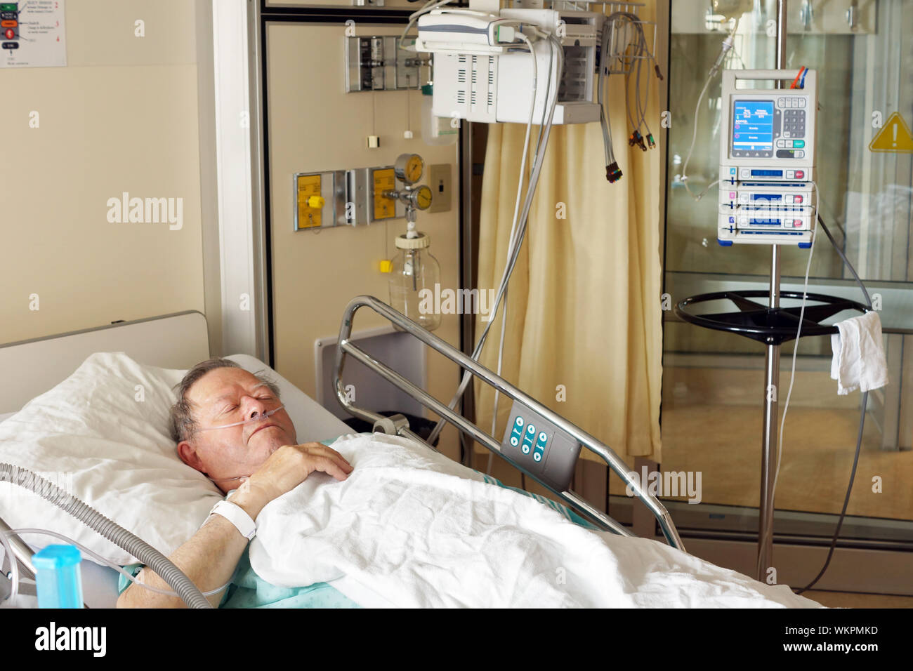 Senior man lying in hospital bed getting oxygen in intensive care unit